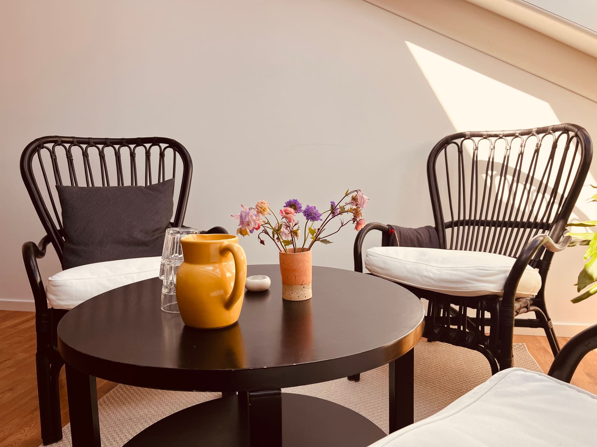 Hyggelig siddegruppe med rattanstole og blomster